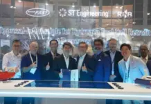 RINA Grants AiP for Hydrogen Fuel Cell Retrofit on Ferry Group of professionals at a conference posing for a photo in front of a banner about hydrogen fuel cell retrofit, with models on the display table and company logos overhead.