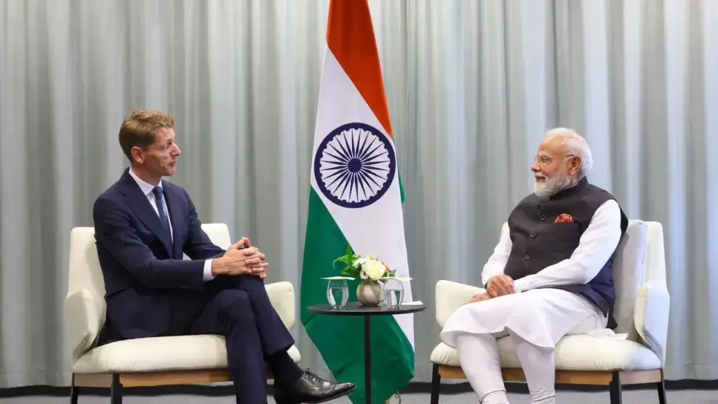 Emmanuel Macron and Narendra Modi sit in chairs for a bilateral meeting, with the Indian flag between them.