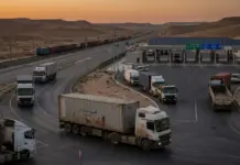 Jordan Advances Efforts to Become Regional Transport Hub Desert highway toll plaza at sunset with a line of semi-trailers waiting to pass.