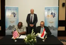 Egypt, Liberia Sign MoU to Boost Regional Civil Aviation Two men sit at a table signing documents; flags of the United States and Egypt on the table, with a man standing behind them and ICAO banners in the background.
