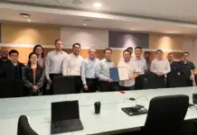 Hitachi Rail Secures Signalling Contract for Singapore NSL Group of professionals posing in a conference room, one person in front holding a certificate folder prominent in the center