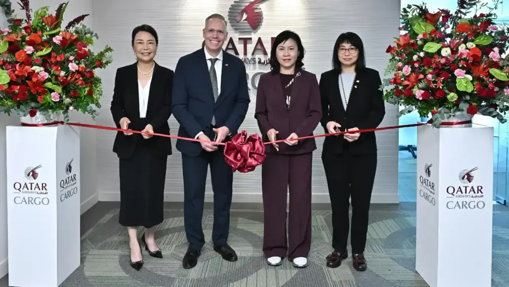 Ribbon-cutting ceremony with four professionals cutting a red ribbon in front of a Qatar Cargo backdrop.