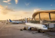 Egypt Pushes Civil Aviation Investment and Airport Growth Airplane parked at a gate beside a curved-glass airport terminal at sunset.